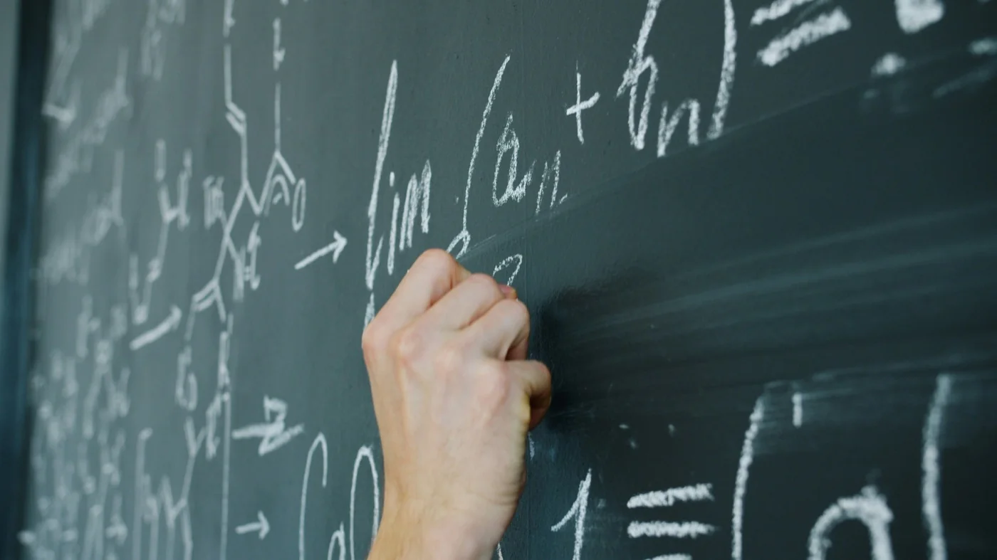 Professor escrevendo fórmulas matemáticas em uma lousa